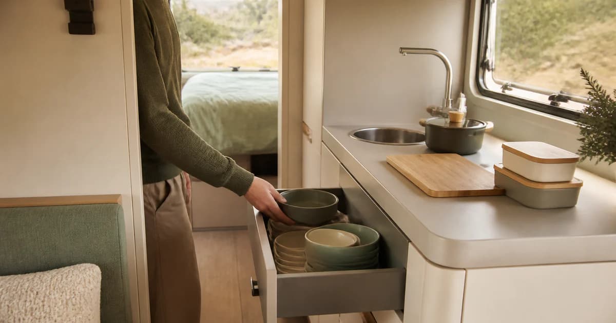 Persona colocando cuencos en un cajón de la cocina de una autocaravana